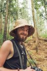 Весёлый путешествующий фотограф фотографирует на фотокамеру во время летних приключений в лесу — стоковое фото