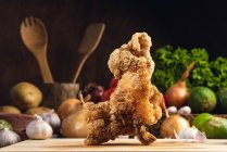 Leckere knusprige gebratene Hühnchen serviert auf Holzschneidebrett auf dem Tisch mit verschiedenen Gemüse in der Küche — Stockfoto