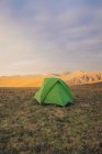 Green camping tent placed on grassy hill in highlands at sunset in Wales — Stock Photo
