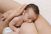 Cropped unrecognizable loving mother breastfeeding newborn while sitting in room at home — Stock Photo