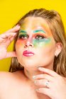Plus size female with bright colorful makeup looking away against yellow background — Stock Photo