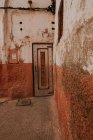 Parede de trituração de casa envelhecida com porta velha na rua de Marraquexe, Marrocos — Fotografia de Stock
