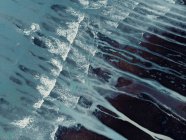D'en haut paysage texturé aérien de rivage accidenté rugueux et pierreux vagues océaniques mousseuses avec des cours d'eau — Photo de stock
