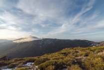 Mountain ridge covered with snow and green forest located against cloudy sky in morning in Sierra de Guadarrama National Park in Madrid, Spain — Stock Photo