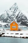 Cabine amarela localizada perto da cordilheira do mar nevado nas ilhas Lofoten, Noruega — Fotografia de Stock