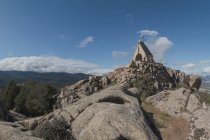 Vista dell'occhio di pesce di montagne sassose e piccolo edificio della chiesa contro il cielo blu nuvoloso nel Parco Nazionale della Sierra de Guadarrama a Madrid, Spagna — Foto stock
