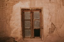 Pared derrumbada de casa envejecida con ventana rota en la calle de Marrakech, Marruecos - foto de stock