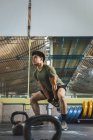 Азіатський чоловік тренує плечі й руки з важкими кетлебелами в спортзалі під час функціонального тренування й озирається геть — стокове фото