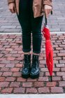 Mulher anônima em roupas casuais e com guarda-chuva em pé na calçada pavimentada na rua da cidade — Fotografia de Stock