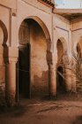 Fassade eines schäbigen islamischen Bogengebäudes mit offener Tür an einem sonnigen Tag auf der Straße von Marrakesch, Marokko — Stockfoto