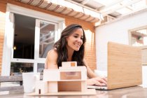 Freelancerin sitzt am Tisch auf der Terrasse und tippt auf Laptop, während sie an einem Remote-Projekt arbeitet — Stockfoto