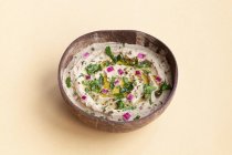 Desde arriba de apetitoso plato tradicional de Baba ghanoush hecho de berenjenas y adornado con hierbas servidas en un tazón sobre fondo beige - foto de stock