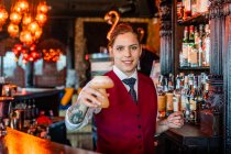 Smiling female barkeeper standing at bar counter with a type of alcohol drink served in creative cocktail glasses in shape of mushroom — Stock Photo