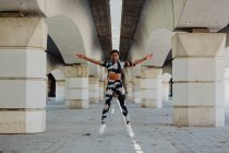 Jeune femme afro-américaine faisant de l'exercice sautant et écoutant de la musique après avoir couru dans la rue de la ville — Photo de stock