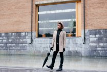 Portrait d'homme élégant noir avec manteau gris et parapluie dans la rue — Photo de stock