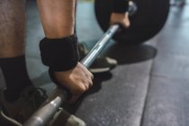 Cortado atleta masculino irreconocible haciendo deadlift con barra pesada durante el entrenamiento en el gimnasio - foto de stock