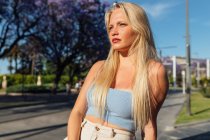 Charmante Frau mit blonden Haaren und trendiger Sommerkleidung steht in der Stadt und schaut weg — Stockfoto