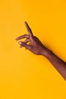 Crop forearm and hand of african-american man raising his index finger against yellow background — Stock Photo
