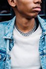 Crop preto na moda macho sério com corrente de prata no pescoço em casaco de ganga azul olhando para longe na rua — Fotografia de Stock