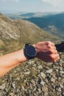 Crop hand of unrecognizable hiker checking time on smartwatch during trekking in highlands on sunny day in Wales — Photo de stock