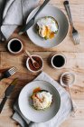 Appetitliche Scheibe Kornbrot mit Avocado und pochiertem Ei auf Platte auf Holztisch gelegt — Stockfoto
