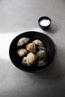 Вид зверху миски з невареними молюсками і сіллю, розміщеними на сірому стільниці під час приготування їжі — стокове фото