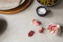 From above top view cloves of ripe garlic and small bowl of salt placed on kitchen table during food preparation — Stock Photo