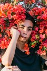 Sereno gay masculino inclinado no mãos e olhando para câmera no verão parque com florescendo flores — Fotografia de Stock