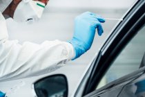 Biólogo com luvas de proteção realizando um teste de coronavírus em uma pessoa em um carro — Fotografia de Stock