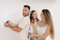 Delighted couple with naked infant and cute little girl standing on white background — Stock Photo