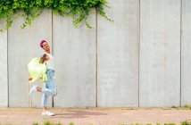 Seitenansicht eines homosexuellen Mannes mit rosa Haaren und Tätowierungen, der im Sommer auf der Straße der Stadt spaziert — Stockfoto