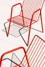Летние красные металлические стулья на белом полу при солнечном свете и тени — стоковое фото