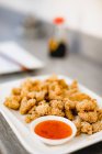 Primi piani pezzi di pollo arrosto croccante posto vicino ciotola con salsa gustosa su sfondo bianco — Foto stock
