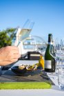 Köstliches und gut dekoriertes Austerngericht gepaart mit Champagner im Restaurant High Cuisine unter freiem Himmel, während die Hand ein Champagnerglas hält — Stockfoto