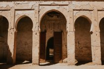 Facciata di squallido edificio islamico ad arco con porta aperta nella giornata di sole sulla strada di Marrakech, Marocco — Foto stock
