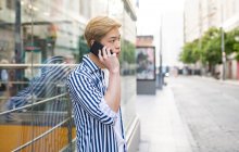 Asian man talking with a cellphone in city street — Stock Photo