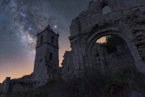 D'en bas des restes ruinés de l'ancien château de pierre avec tour sous le ciel étoilé de la nuit avec la Voie lactée — Photo de stock