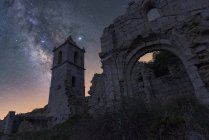 De baixo de restos arruinados de castelo de pedra antiga com torre sob céu estrelado noite com Via Láctea — Fotografia de Stock