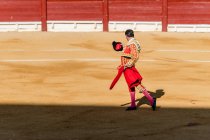 Visão traseira de toureiro irreconhecível em fantasia tirando chapéu após desempenho corrida enquanto em pé na arena arenosa — Fotografia de Stock
