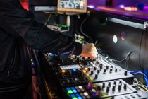 Desde arriba hombre de la cosecha jugando profesional de dos canales DJ controlador mientras se realiza en concierto en el club nocturno moderno - foto de stock