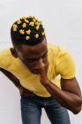 Красивый афроамериканец с жёлтыми цветами в волосах, трогательная шея и взгляд сверху на белом фоне — стоковое фото