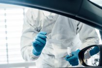 Biólogo com luvas de proteção realizando um teste de coronavírus em uma pessoa em um carro — Fotografia de Stock
