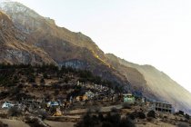 Величественный пейзаж поселка с жилыми домами, расположенными на скалистом склоне Гималаев в Непале утром — стоковое фото