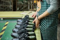 Detalle de las manos de la mujer mientras revisa los zapatos en la línea de producción de control de calidad en la fábrica de zapatos chinos - foto de stock