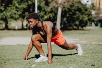 Young fitness African American woman preparing for running and making exercise on park — Stock Photo