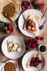 De acima mencionadas chapas de crepes saborosos com coberturas variadas colocadas na mesa de madeira durante o café da manhã — Fotografia de Stock