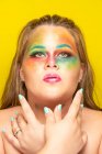 Plus size female with bright colorful makeup looking away against yellow background — Stock Photo