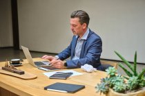 Designer am Schreibtisch, der mit seinem Tablet am Computer arbeitet — Stockfoto