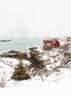 Cabañas rojas situadas en la costa nevada de la cordillera en las Islas Lofoten, Noruega - foto de stock