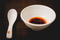 Bowl of spicy chili sauce on wooden table — Stock Photo
